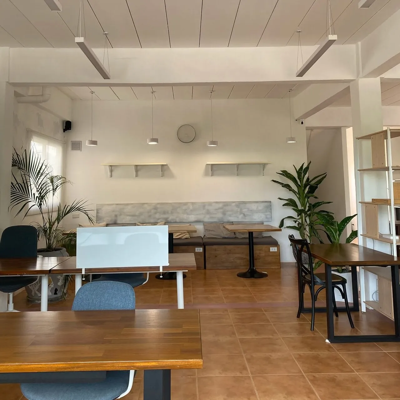Open coworking floor with tables, office chairs, and natural light